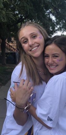 Hannah Peterson and Zoe Kang embrace outside Boulder High, decked in spirit gear