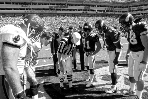 NFL players look intently to the ground to see the result of the coin toss.