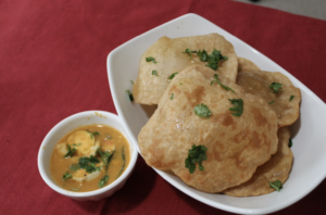 Puris are small, round, flat pieces of bread made of unleavened wheat flour, deep-fried, and served with egg curry, which is made with hard-boiled eggs, onions, tomatoes, whole & ground spices, and herbs.