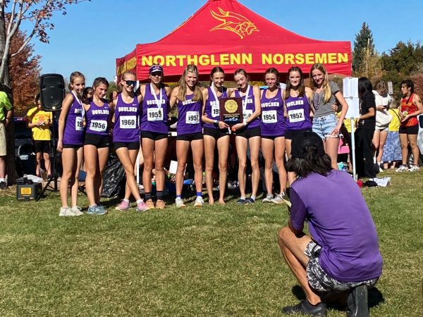Coach Geo Tam takes a photo of the Girls Cross Country team holding a medal after yet another amazing race this season.