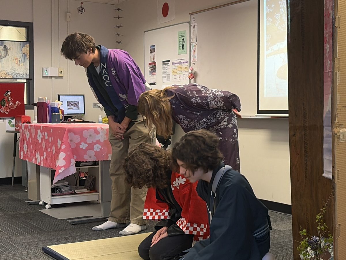 AP Japanese students Beau Dunbar, '26, Helena Carr, '27, Olive Tromey, '27, and Caspian Polaris, '29, bow to Governor Polis and other guests at the end of their presentation, demonstrating the Japanese value of humility.