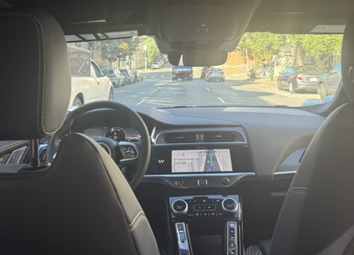 A Waymo heads smoothly down one of the many steep hills in San Francisco, as rider Madison Sanford snaps a picture of the empty driver's seat.